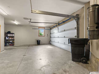 This spacious garage offers ample storage with a tall shelving unit and a built-in central vacuum system.