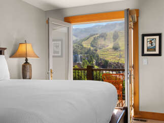 Wake up to breathtaking mountain views from this stunning bedroom, featuring a comfortable bed and direct access to a private balcony.