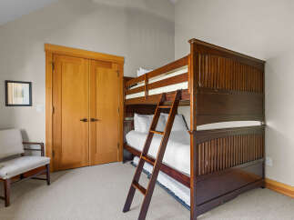 This charming bedroom features a sturdy wooden bunk bed with crisp white linens, perfect for accommodating guests or family.