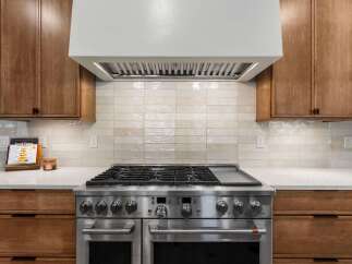 Experience culinary excellence in this stunning kitchen, featuring a professional-grade stainless steel range with a griddle top.