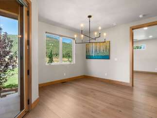 Experience breathtaking mountain views from this elegant dining room, featuring a modern chandelier and a vibrant abstract artwork.