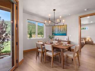 Experience modern living with this stunning dining area, featuring a sleek chandelier and a vibrant abstract artwork.