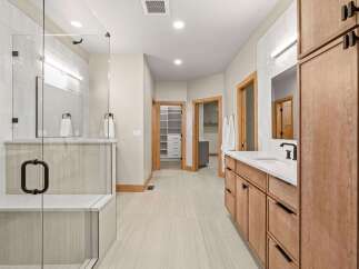 Experience luxury in this spacious master bathroom, featuring a walk-in glass shower with a built-in bench and elegant tilework.