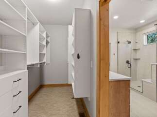Step into this luxurious walk-in closet featuring ample white shelving and built-in drawers, perfect for organizing your wardrobe.