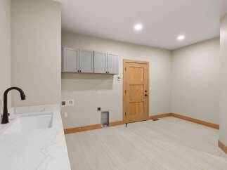 Discover this spacious laundry room, featuring a sleek white countertop with an undermount sink and a modern dark faucet.