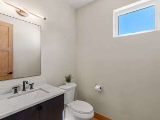This modern bathroom features a sleek vanity with a marble countertop and a stylish faucet, complemented by a large mirror and contemporary lighting.