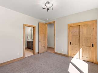 This spacious bedroom features a modern chandelier and a large sliding closet.