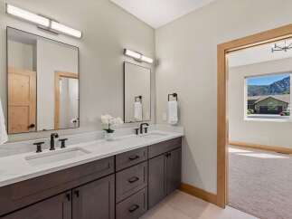 Experience luxury in this modern bathroom featuring a spacious double vanity with quartz countertops and sleek dark wood cabinetry.