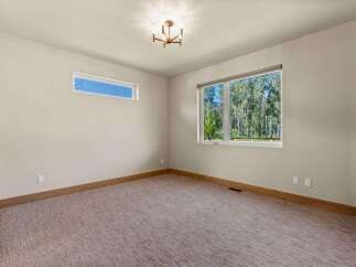 Experience the serene beauty of nature from this spacious room, featuring large windows that offer breathtaking views of a lush forest.