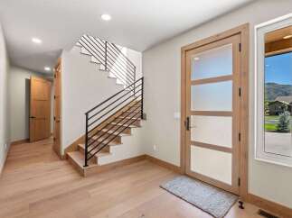 Step into a modern entryway featuring a sleek staircase with black metal railings and warm hardwood floors.