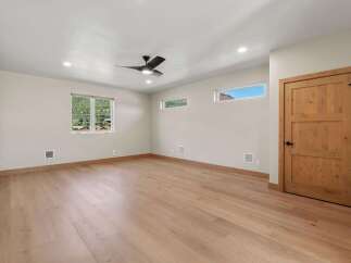 Experience modern living in this spacious room featuring a sleek ceiling fan and recessed lighting.