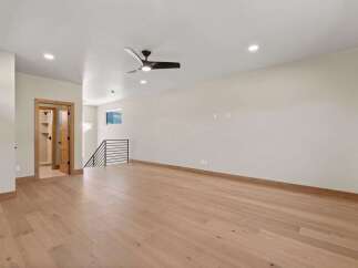 Experience modern living in this spacious, open-concept room featuring elegant hardwood floors and a sleek ceiling fan.
