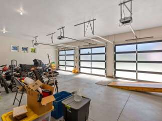 This spacious garage offers ample storage and parking with three modern, frosted glass garage doors that allow natural light to fill the space.