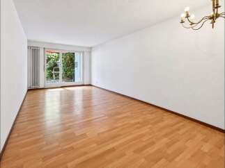 Experience bright and airy living in this spacious room featuring gleaming hardwood floors and large sliding glass doors that open to a lush garden view.
