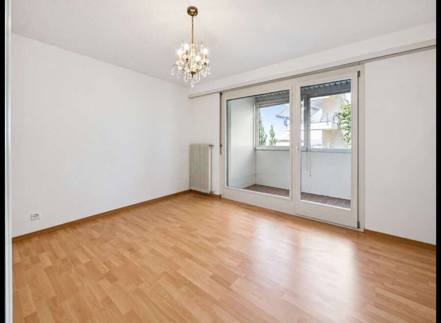 Bright and airy room with gleaming hardwood floors and a modern chandelier.