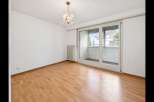 Bright and airy room with gleaming hardwood floors and a modern chandelier.