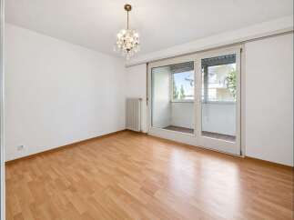 Bright and airy room with gleaming hardwood floors and a modern chandelier.