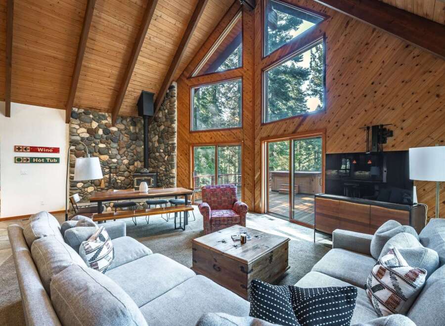 Experience rustic charm in this spacious living area, featuring a soaring wood-paneled A-frame ceiling and a striking stone fireplace.