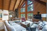 Experience rustic charm in this spacious living area, featuring a soaring wood-paneled A-frame ceiling and a striking stone fireplace.