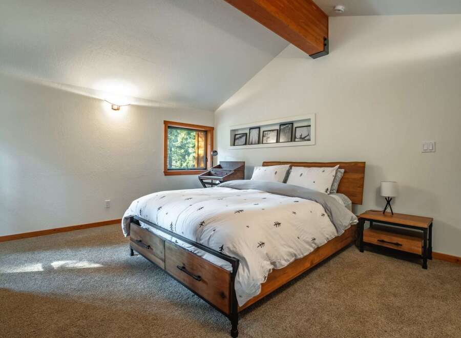 Experience rustic charm in this inviting bedroom, featuring a comfortable bed with a unique tree-patterned duvet and matching pillows.