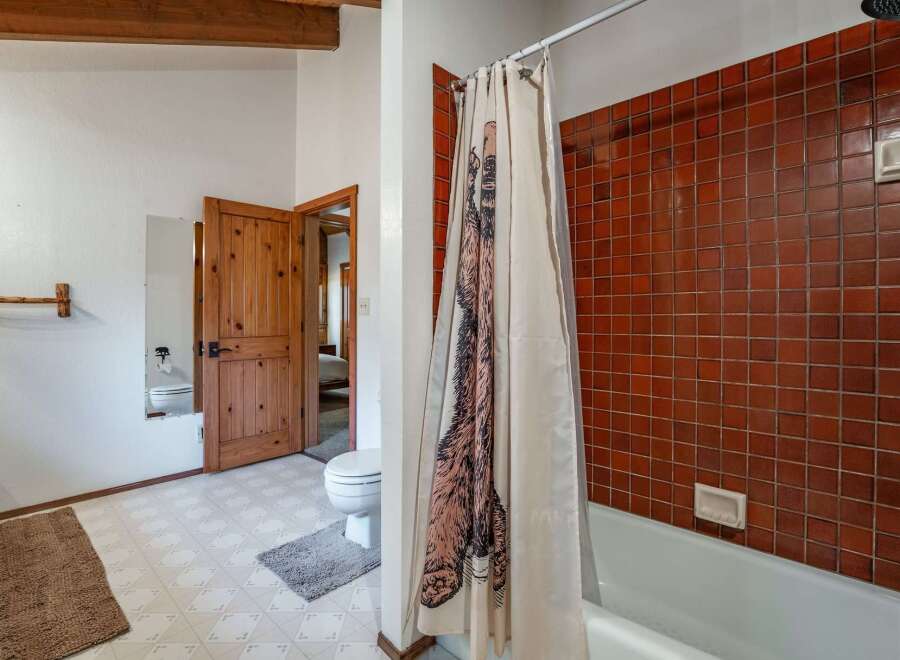 This rustic bathroom features a charming wooden door and exposed beams, adding a touch of natural warmth.