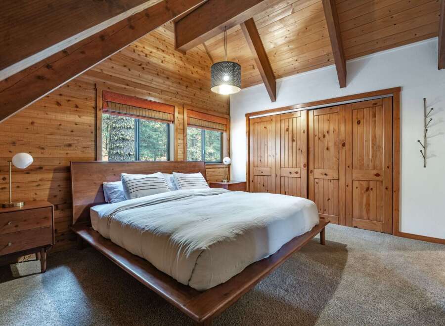 Experience rustic charm in this cozy bedroom featuring warm wood paneling and exposed beams.
