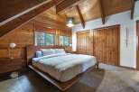 Experience rustic charm in this cozy bedroom featuring warm wood paneling and exposed beams.