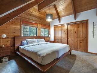Experience rustic charm in this cozy bedroom featuring warm wood paneling and exposed beams.