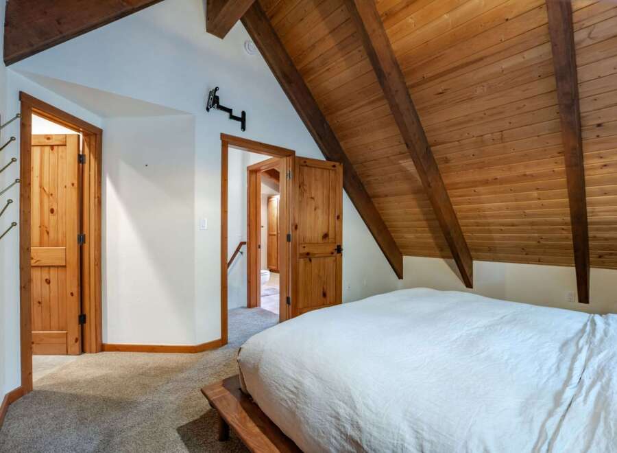 Experience rustic charm in this cozy bedroom featuring a vaulted wood-paneled ceiling and exposed beams.
