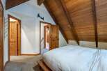 Experience rustic charm in this cozy bedroom featuring a vaulted wood-paneled ceiling and exposed beams.