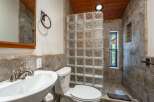 Experience rustic charm in this bathroom featuring a unique glass block shower enclosure and warm wood-paneled ceiling.