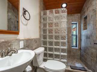 Experience rustic charm in this bathroom featuring a unique glass block shower enclosure and warm wood-paneled ceiling.