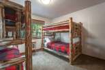 Experience rustic charm in this cozy cabin bedroom featuring sturdy log bunk beds with classic red and black buffalo plaid bedding.