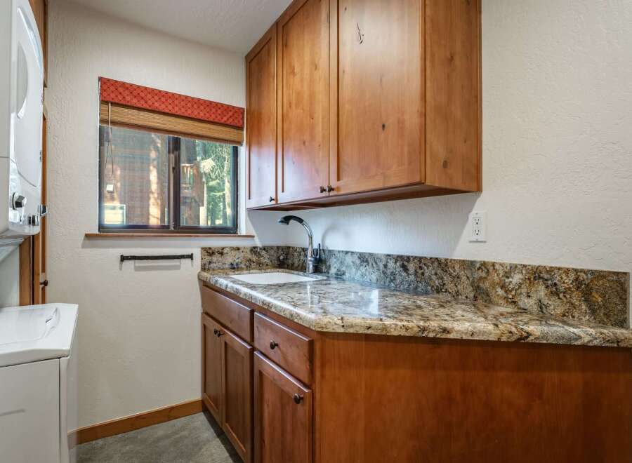 This laundry room features a convenient built-in sink and ample storage with custom wooden cabinetry.