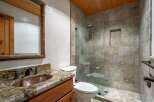 Experience rustic charm in this bathroom featuring a copper vessel sink atop a granite countertop and a wooden vanity.