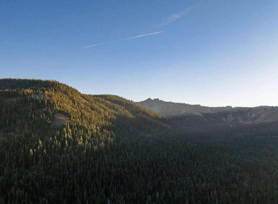 Experience breathtaking mountain vistas from this stunning property, nestled amidst a dense forest of evergreen trees.