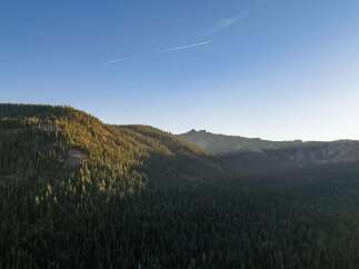 Experience breathtaking mountain vistas from this stunning property, nestled amidst a dense forest of evergreen trees.