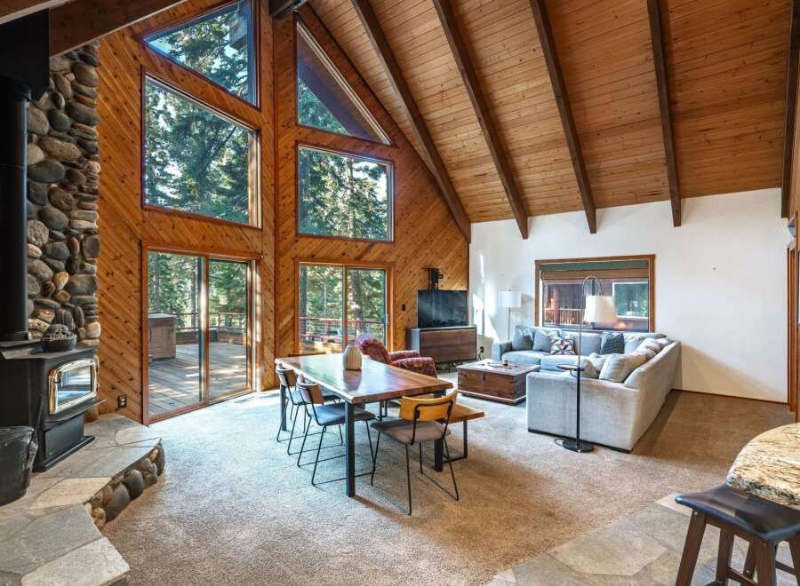 Experience rustic charm in this stunning mountain retreat, featuring a grand stone fireplace and soaring vaulted ceilings with exposed wooden beams.