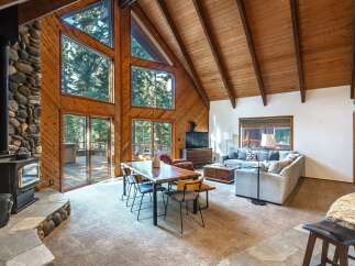 Experience rustic charm in this stunning mountain retreat, featuring a grand stone fireplace and soaring vaulted ceilings with exposed wooden beams.
