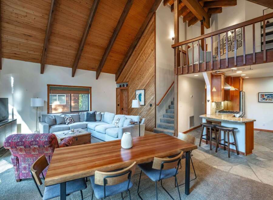 Experience rustic charm in this spacious living area featuring a vaulted wood-paneled ceiling and a large sectional sofa perfect for gatherings.