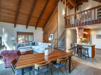 Experience rustic charm in this spacious living area featuring a vaulted wood-paneled ceiling and a large sectional sofa perfect for gatherings.
