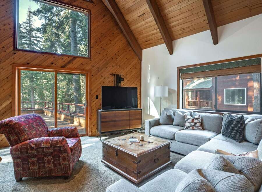 Experience rustic charm in this inviting living room, featuring a vaulted wood-paneled ceiling and a large stone fireplace.