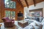 Experience rustic charm in this inviting living room, featuring a vaulted wood-paneled ceiling and a large stone fireplace.