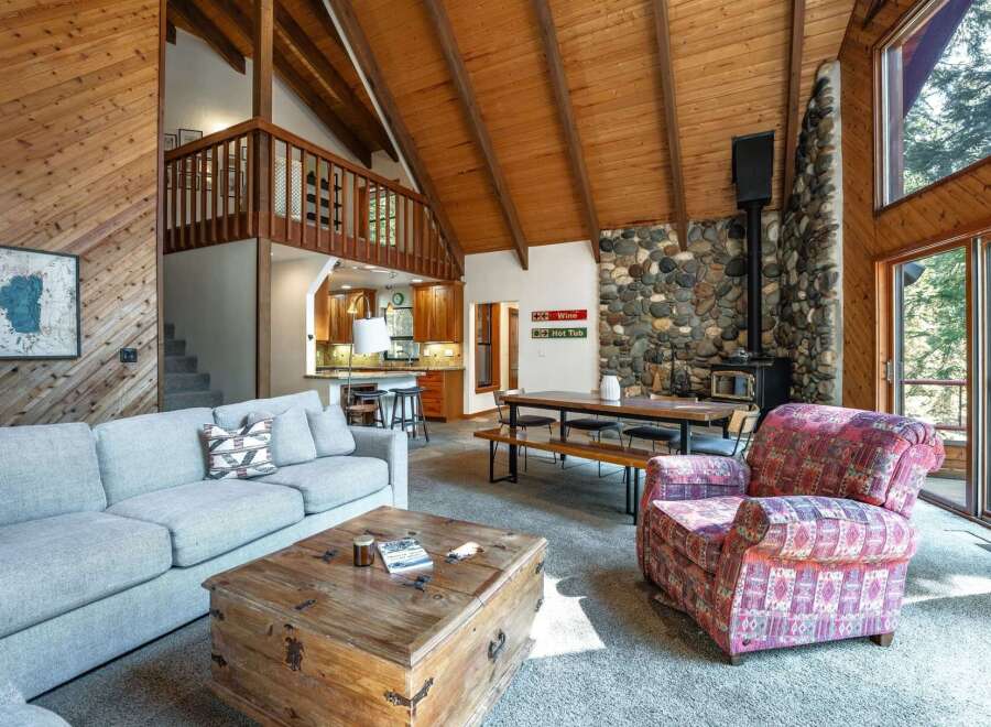 Experience rustic charm in this spacious living area featuring a grand stone fireplace and a soaring vaulted wood-beamed ceiling.