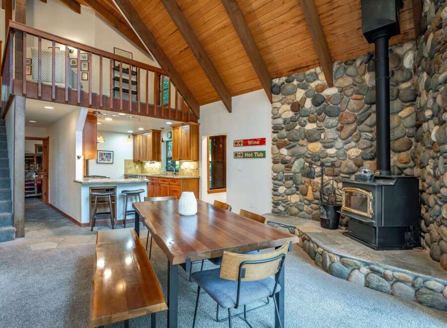 Experience rustic charm in this spacious living area, featuring a stunning floor-to-ceiling stone fireplace and a cozy wood-burning stove.