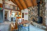 Experience rustic charm in this spacious living area, featuring a stunning floor-to-ceiling stone fireplace and a cozy wood-burning stove.