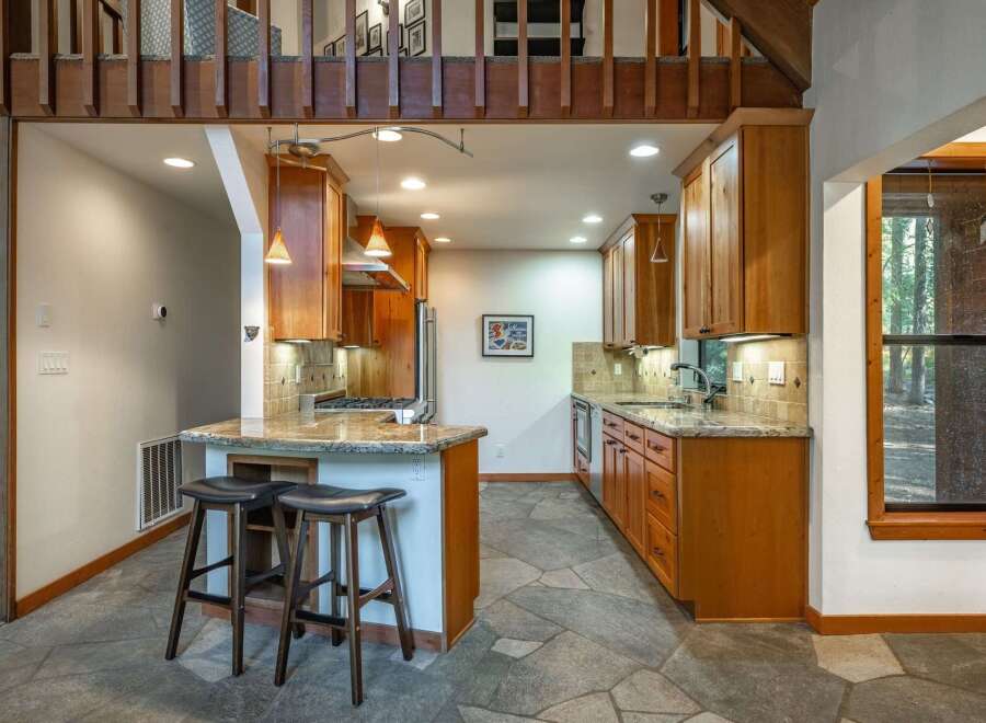 This charming kitchen boasts warm wooden cabinetry and granite countertops, creating a cozy and inviting atmosphere.
