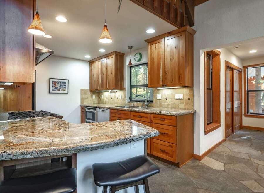 This spacious kitchen boasts beautiful granite countertops and warm, custom wood cabinetry, offering ample storage and a luxurious feel.