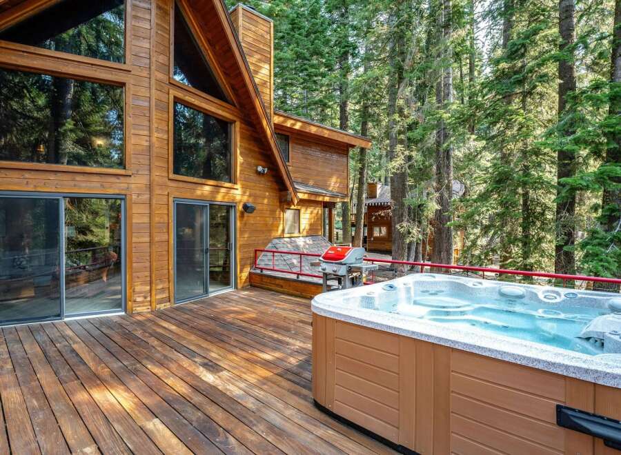 Experience ultimate relaxation in this stunning mountain retreat, featuring a spacious wooden deck with a luxurious hot tub and a gas grill, perfect for entertaining.