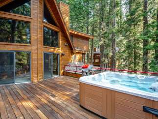 Experience ultimate relaxation in this stunning mountain retreat, featuring a spacious wooden deck with a luxurious hot tub and a gas grill, perfect for entertaining.
